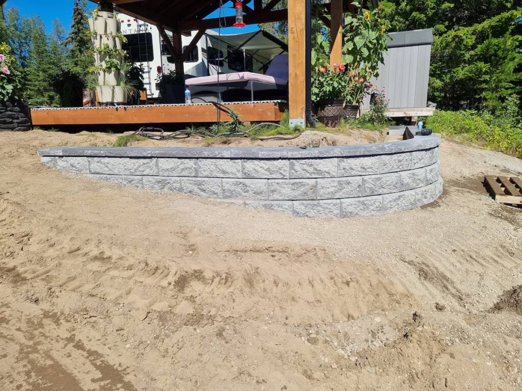 The finished corner of a structural tiered retaining wall made of grey blocks, engineered for slope stability in Prince George.