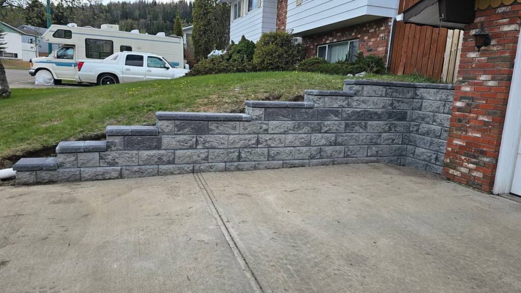 A structural concrete block retaining wall built on a sloped residential property in Prince George, BC.