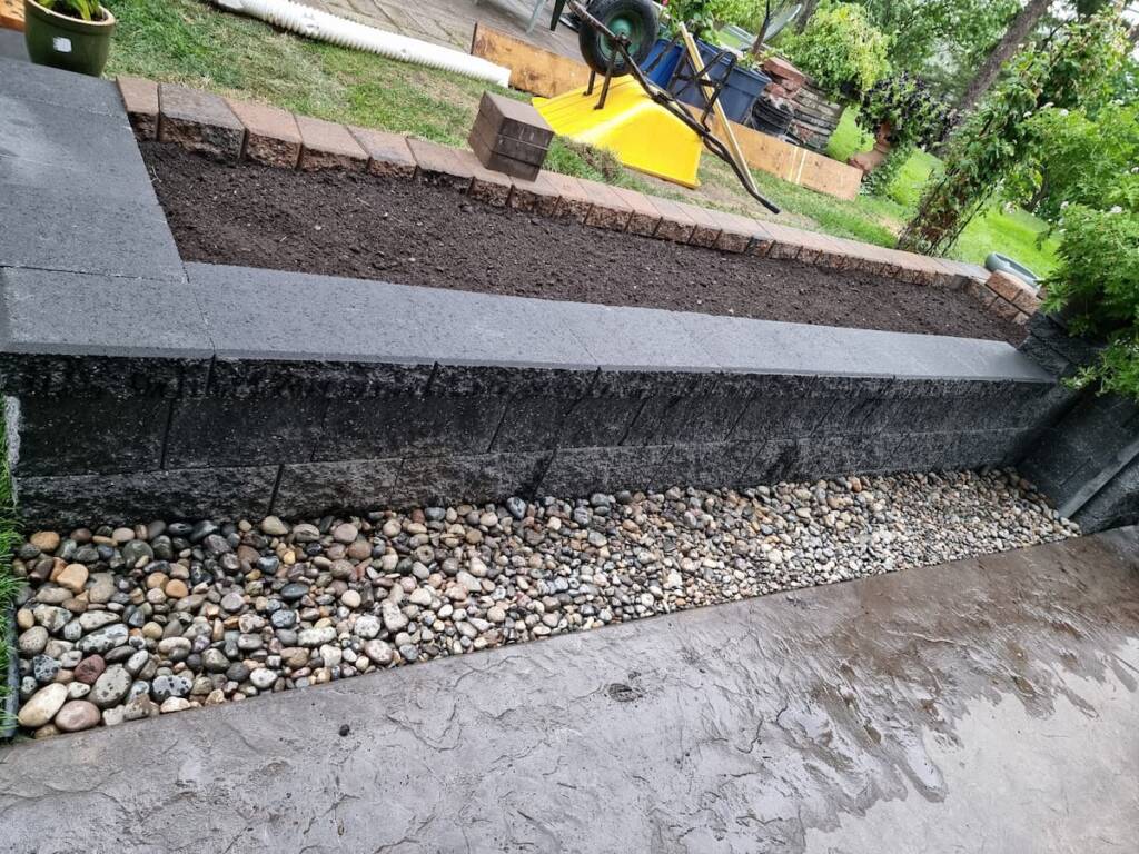 A decorative multi-level concrete block planter box integrated into a paving stone patio design in Prince George, BC.