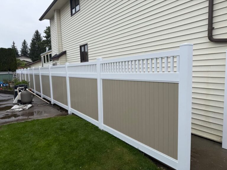 Durable tan and white vinyl privacy fence with accent lattice top installed next to residential siding in Prince George